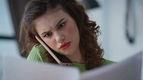 Closeup Nervous Manager Calling Mobile Phone Flipping Papers at Office Table