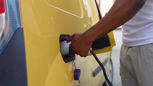 Black Man Disconnects Power Connector Into Cargo EV Car Close Up