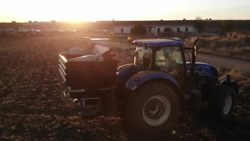 Tractor Farming in Countryside Field at Sunset
