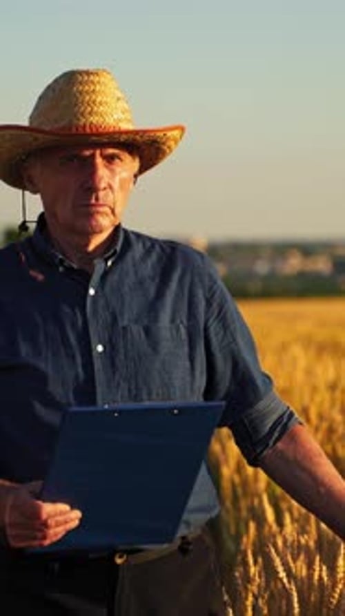 Man Holding Clipboard in Golden Wheat Field