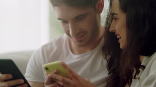 Loving couple using smartphones together indoors