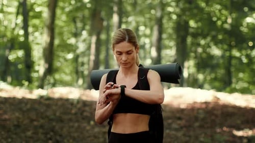 Woman Hiking in the Woods With a Yoga Mat and Backpack on a Sunny Day