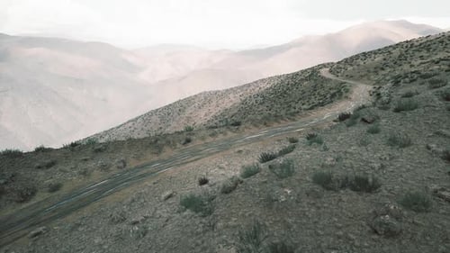 Route de montagne sinueuse à travers la région du Pamir au Tadjikistan sous un ciel nuageux