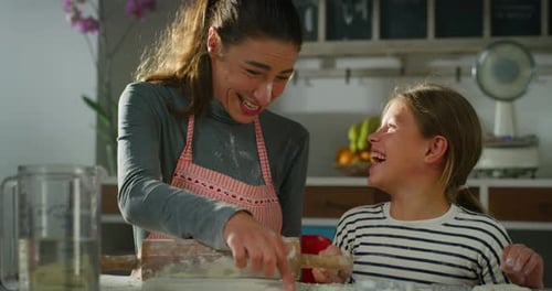 Portrait of Mother and Daughter in the Kitchen Baking Together. Playful Little Girl Putting Fl
