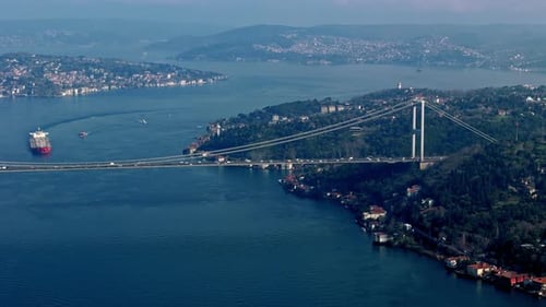 Drone View of Cargo Ship Sailing Through the Bosphorus with Bridge Background
