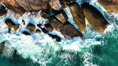 Des vagues écrasent les rochers de la plage.