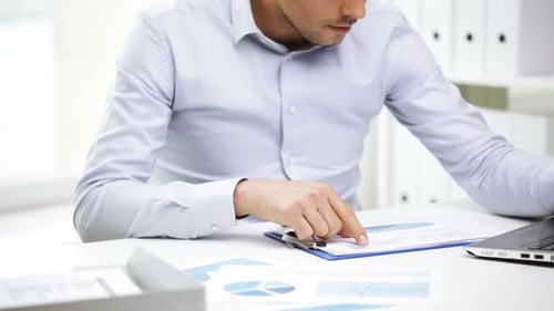 Busy hispanic businessman working with laptop and papers in modern office