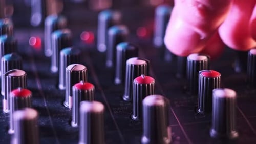Male Hand Adjusting Buttons on Audio Mixer in Neon Light CloseUp