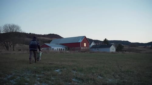 Man Pushes Wheelbarrow Full of Wood on Farm