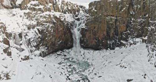 Felsiger schneebedeckter Berg mit kaskadierendem Wasserfall