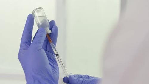 Hand Holding Syringe and Vaccine Ampoule with a Vaccine Health Care