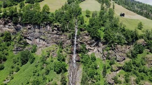 Aerial view of Fallbach Waterfall flowing through green mountains in Austria 4K