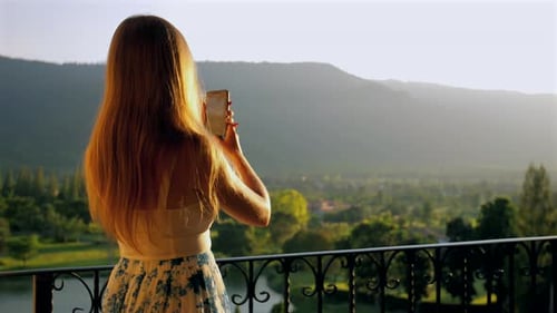 Woman Taking Photos of Tropical Mountain View at Sunset