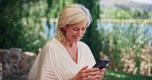 Senior woman laughs while using cell phone outdoors