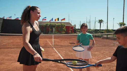 Woman Teaches Tennis to Children on Tennis Court