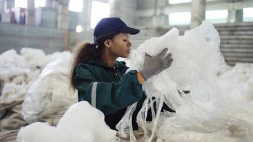 An AfricanAmerican Woman in a Special Uniform Sorts Polyethylene at a Waste Recycling Plant