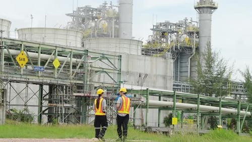 Engineers Inspecting Industrial Plant on Overcast Day