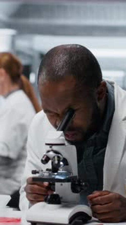 Man Using Microscope in a Brightly Lit Laboratory