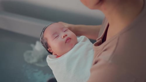 Mother washing baby hair. Mom cleaning her baby hair with shampoo in plastic tub in bathroom at home