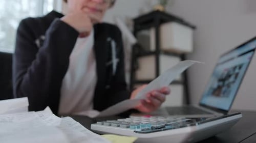 Woman Checking Bills Taxes Bank Account Balance and Calculating Expenses in the Living Room at Home