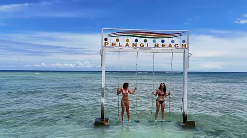 Women on Swings at Tropical Beach