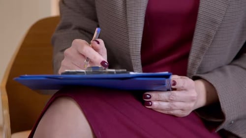 Gros plan d'une psychothérapeute prenant des notes dans le bloc-notes pendant la session