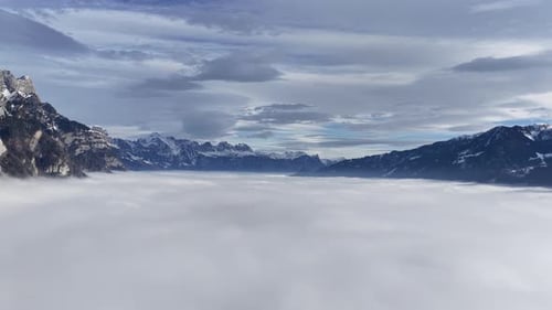Churfirsten mountains rising above fog layer near Walensee Switzerland drone aerial