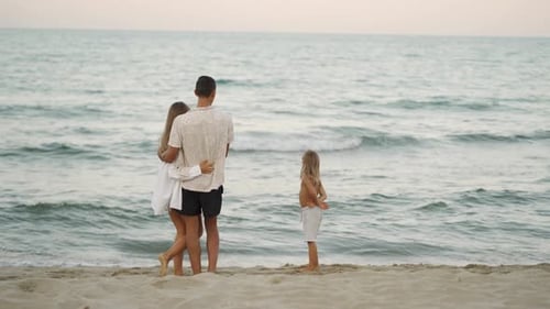 Happy Family Enjoying a Peaceful Day at the Beach Standing Together and Watching the Waves Parents
