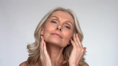 Attractive Mature Woman Applying Skincare Cream to Face