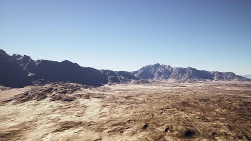 Expansive Arid Desert with Jagged Mountain Ranges Under Clear Sky
