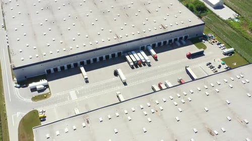 Aerial Shot of Industrial Warehouse Loading Dock where Many Truck with Semi Trailers Load Merchandis