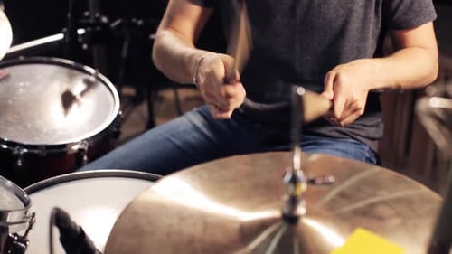 Energetic male musician playing snare drum and hi-hat cymbal at rock concert