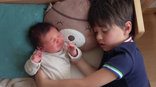 Boy Holding Crying Infant in Nursery