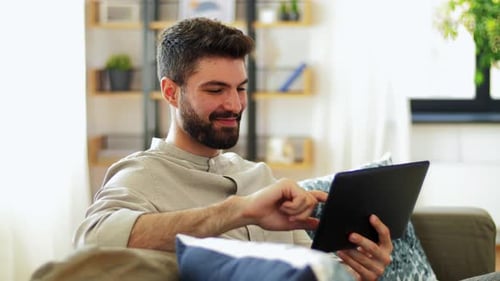 Man Relaxing on Sofa Using Digital Tablet Device