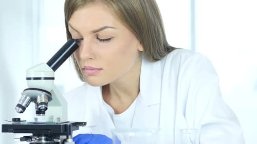 Woman Using Microscope in Laboratory Research