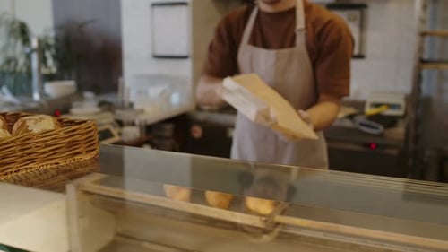 Bakery Worker Packing Pastry in Paper Bag and Giving to Customer