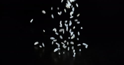Rice Being Poured Downward on Black Background