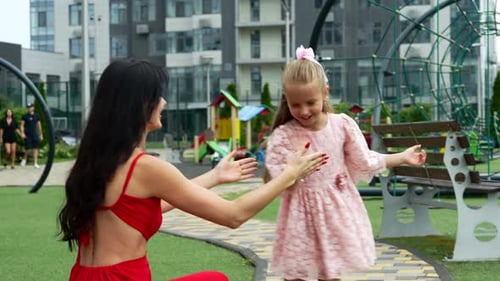 Mother and Daughter Enjoying Joyful Playtime at City Park Playground on a Sunny Day