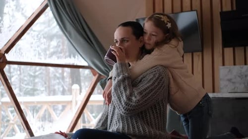 Loving Mother and Child Hug Indoors on Snowy Day
