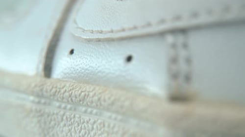 A close-up shot of a white sneaker sole, miniature shoe display on a 360 rotating stand with reflect