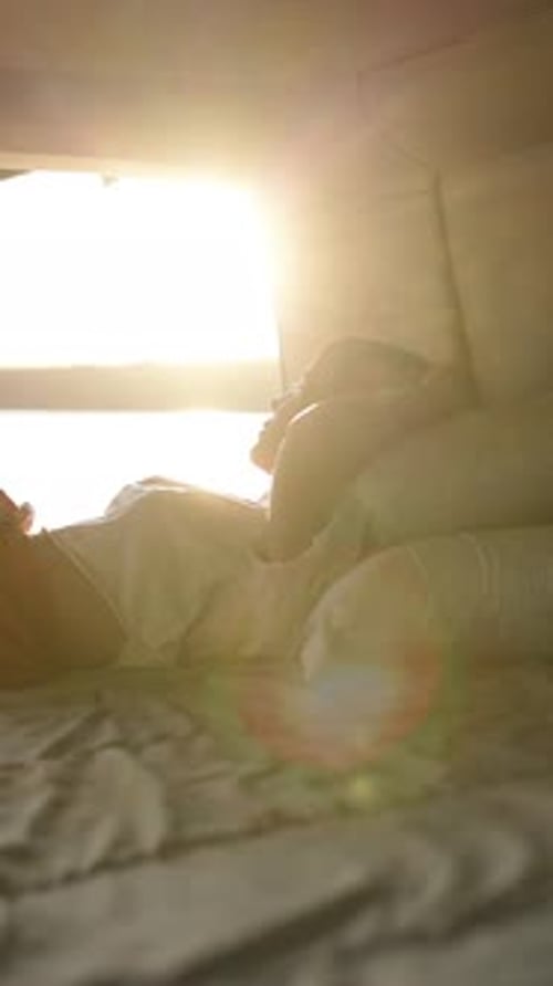 Femme se réveillant dans son lit avec la lumière du soleil qui traverse la fenêtre