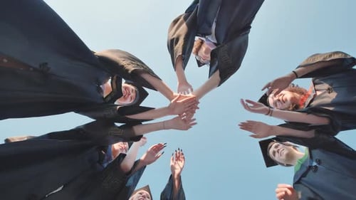 Smiling Graduates Celebrate Success with a Team Huddle