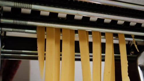 Woman Using Pasta Machine to Make Fresh Pasta Dough in the Kitchen Cooking in Italian Restaurant
