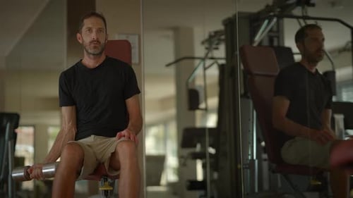 A Man Engaged in Lifting Weights at the Gym Deeply Reflecting on His Fitness Journey and Progress