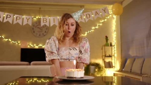 Woman Blowing Out Birthday Candle at Home