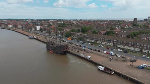 Aerial View of Historic Tall Ship Docked at Urban Riverfront