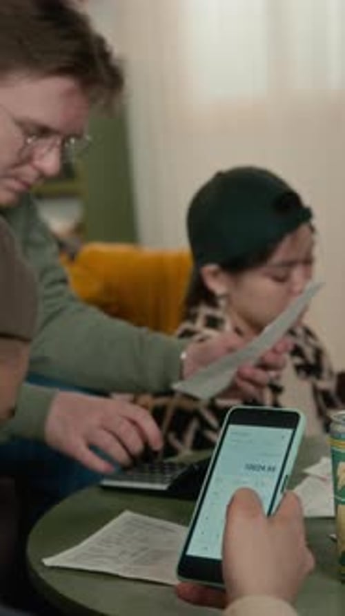 Multiethnic Students Calculating Utility Bills on Smartphone