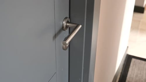 Hand opens a gray door with silver handle