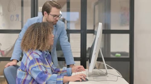 Businessman Guiding African Woman while Working on Desktop