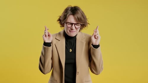 Stylish Young 30s businessWoman or Student Lady Praying with Crossed Fingers Yellow Background Lady